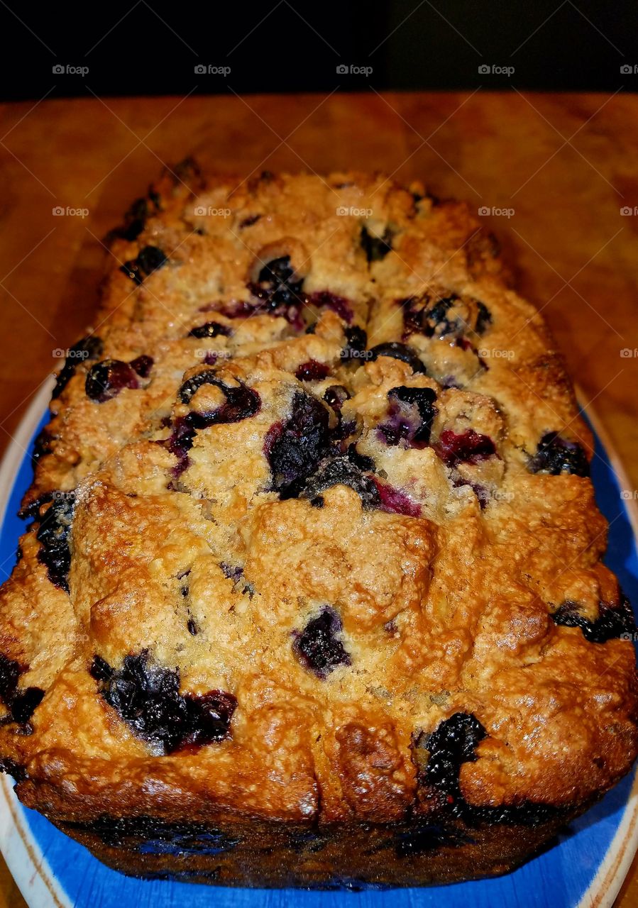 Homemade baked blueberry nut bread on a blue dish.