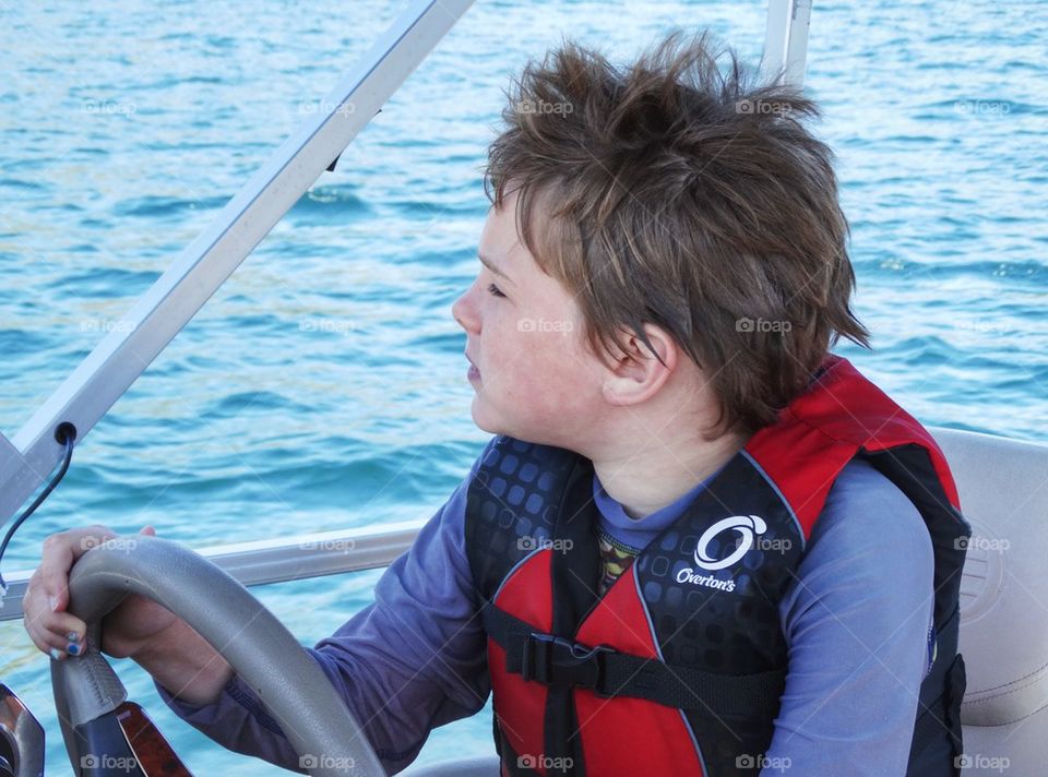 Young Boy Driving A Motorboat
