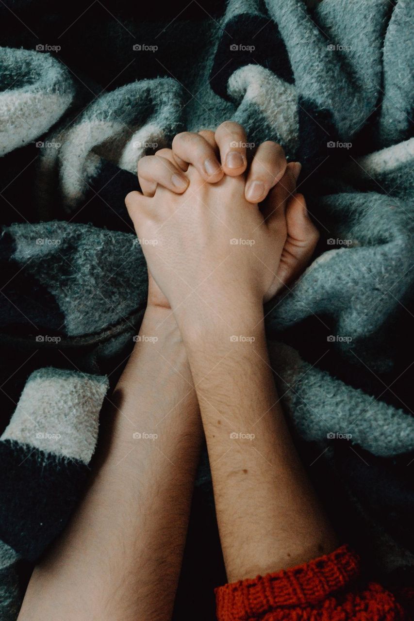 Their hands clasp tightly together as they lie on the soft blue blanket.