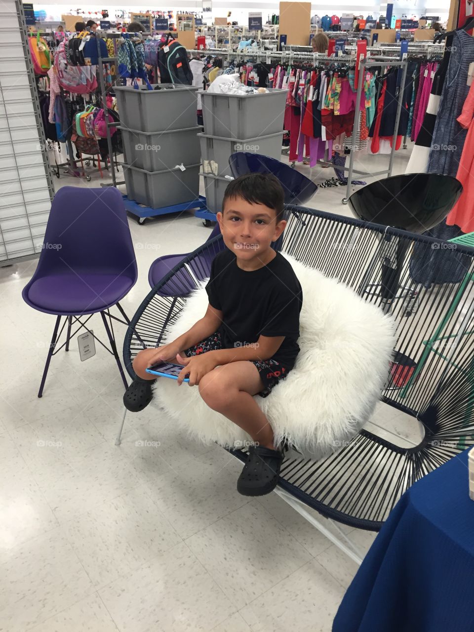 Boy sitting by furniture display at mall