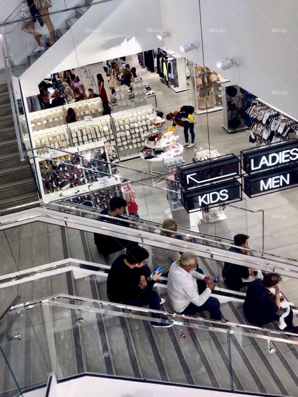 Men sit on the steps of the mall waiting their shopping women