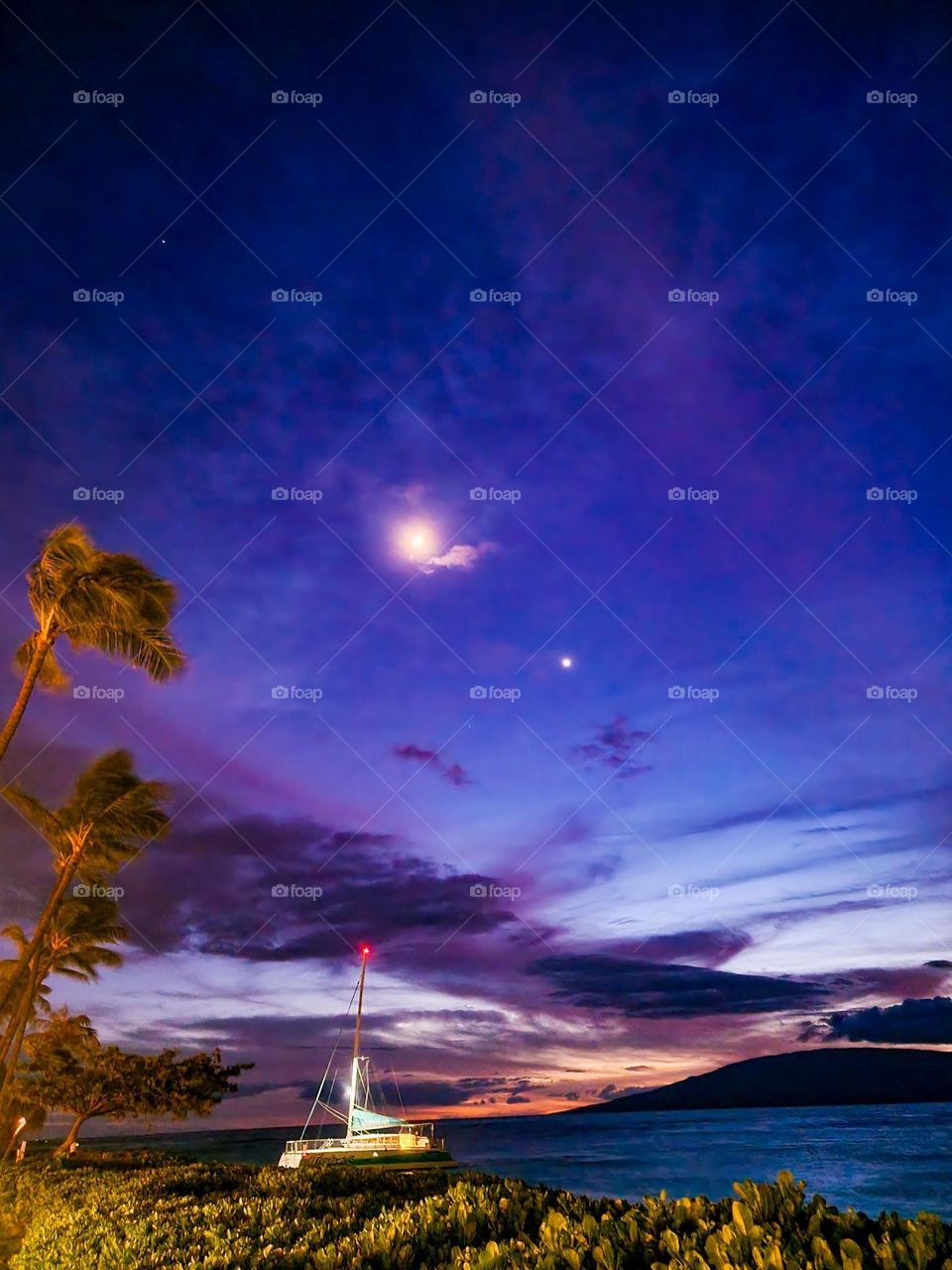 The moon and Venus shining so brightly in the sky at dusk with a hint of purple in Maui Hawaii.
