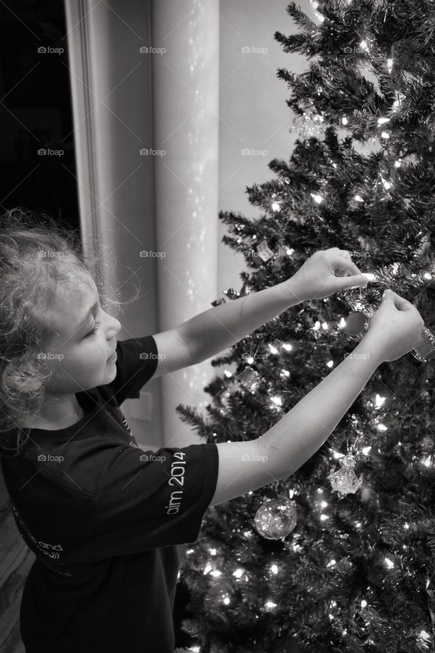 Black and white, child, girl hanging Christmas tree ornaments 