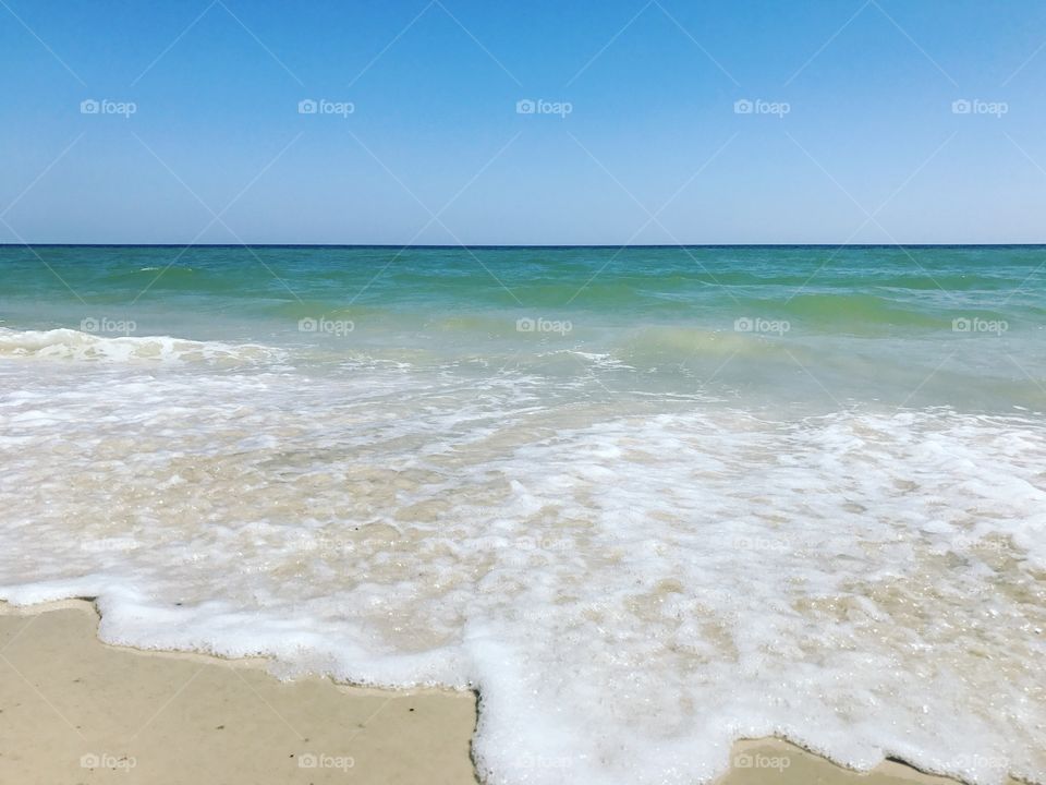 White sand foam water blue green ocean.