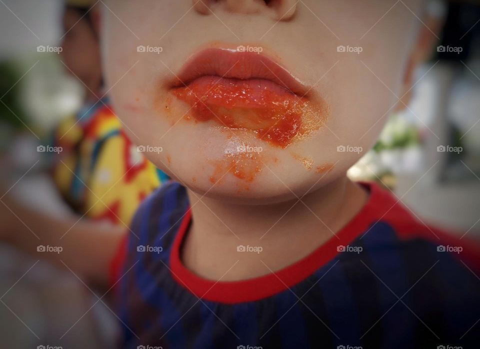 close-up of child's lips covered in tomato sauce