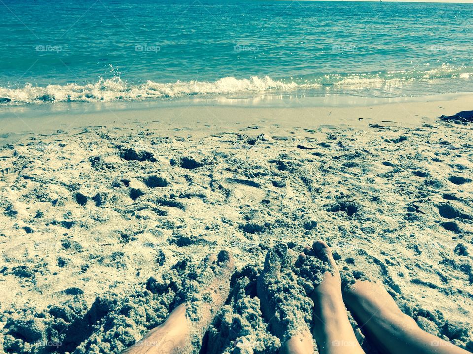 Couples feet in the sand enjoying the beach.