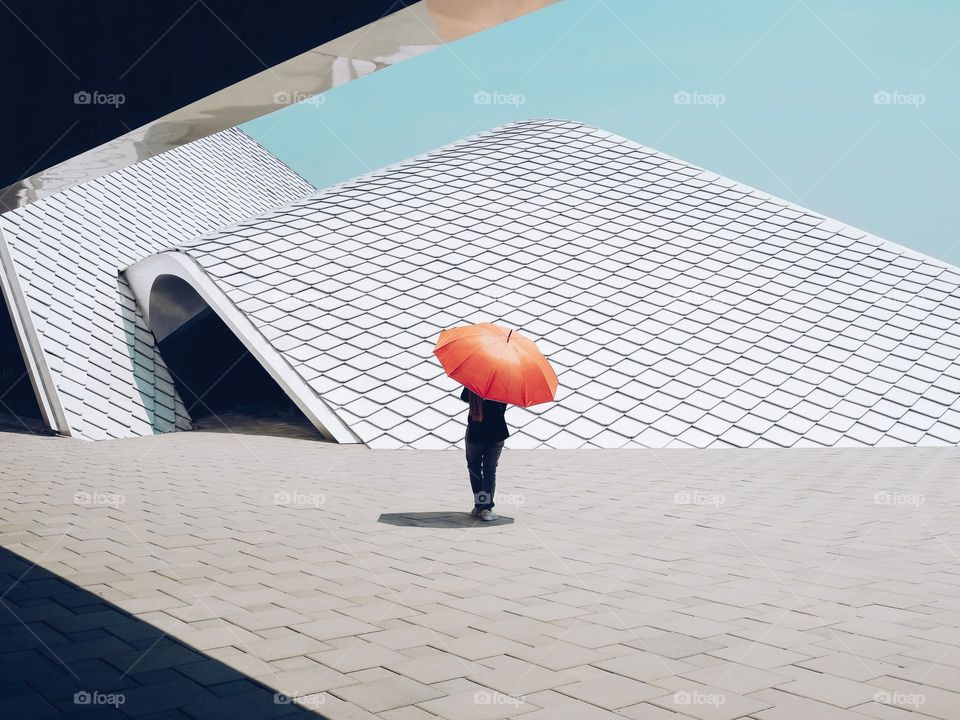 Lady with a red umbrella to sheild herself against the bright sunny heat