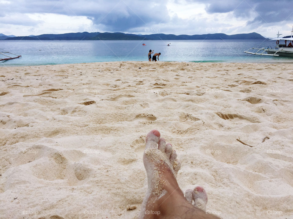 Feet on white sand beach