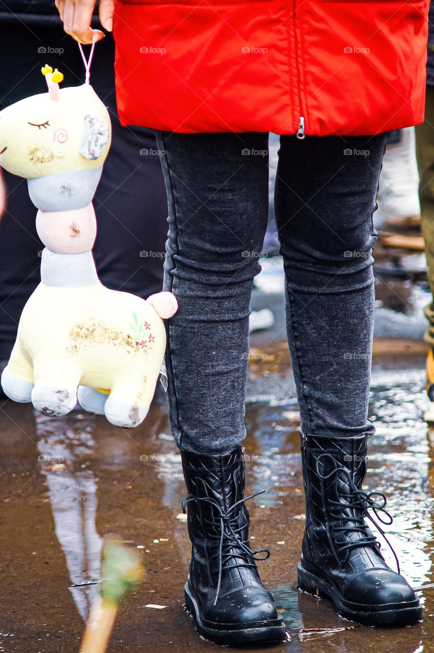 Girl in the rain holding a dirty toy