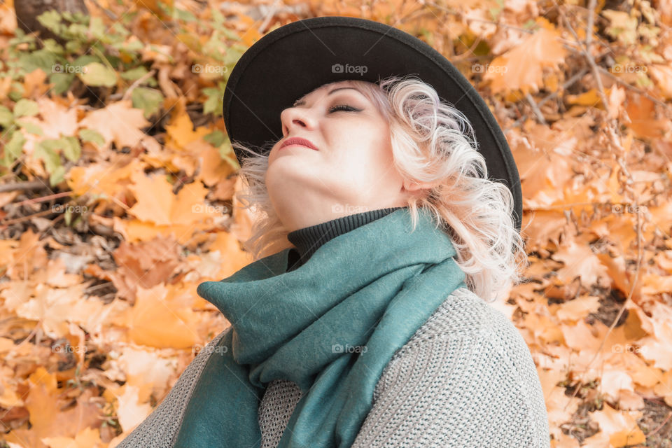 Autumn portrait of adult middle-aged woman in black hat and autumn clothes