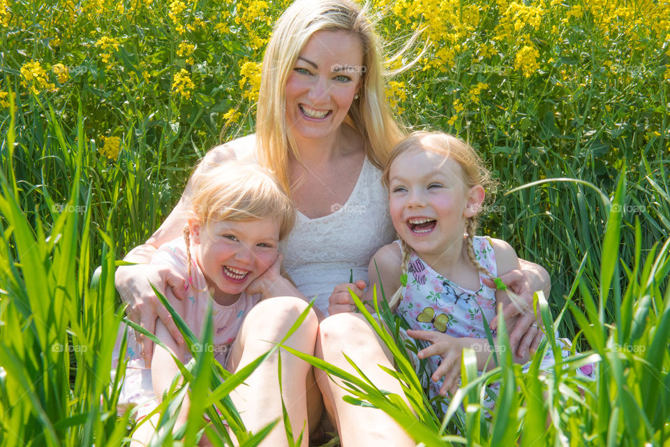 Happy mother with her two daughters sitting in field