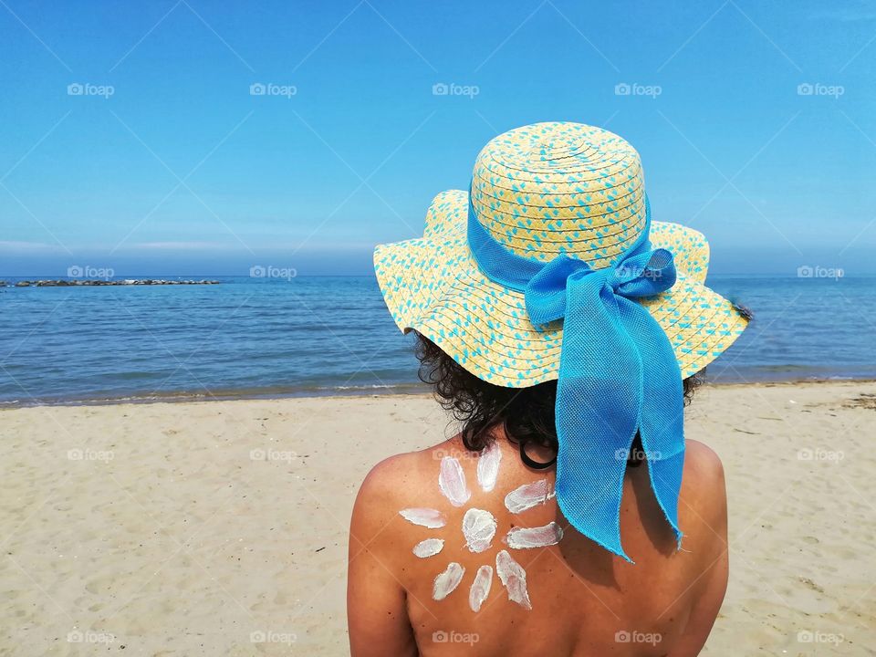 girl sunbathes and protects herself with sunscreen and hat