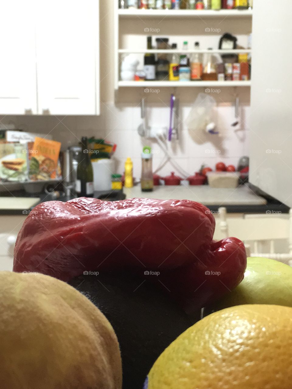 What's cooking? About to charbroil some fresh red capsicum for dinner; red capsicum foreground blurred kitchen background 