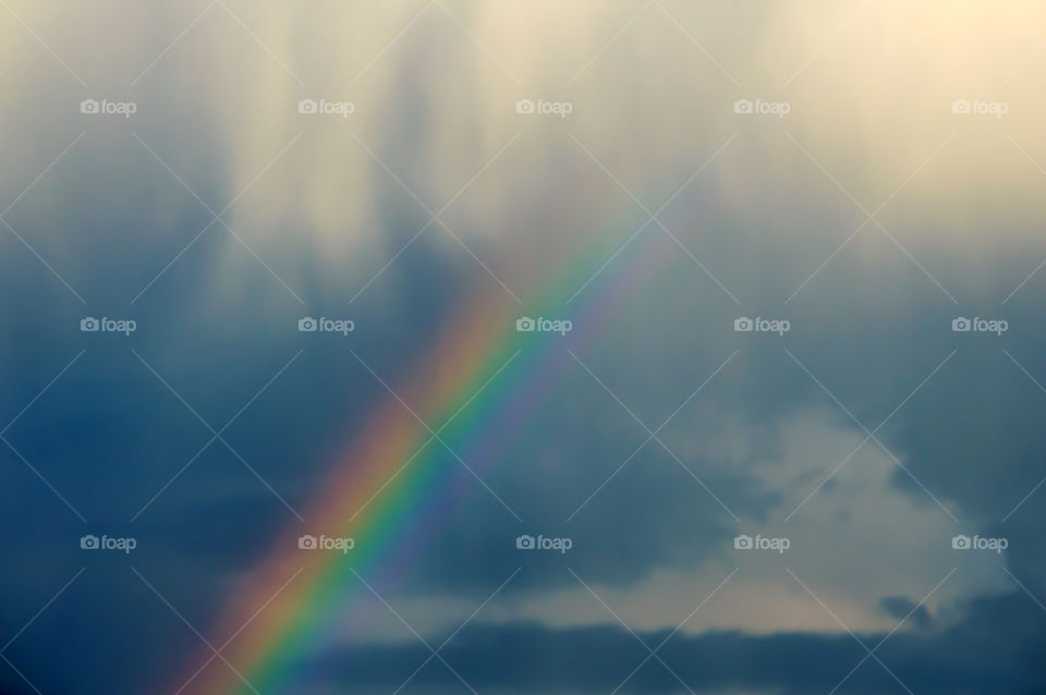 Rainbow in the clouds in a stormy sky with white clouds pouring down in dreamlike cloudscape, nephology and physics scientific phenomena landscape nature photography 