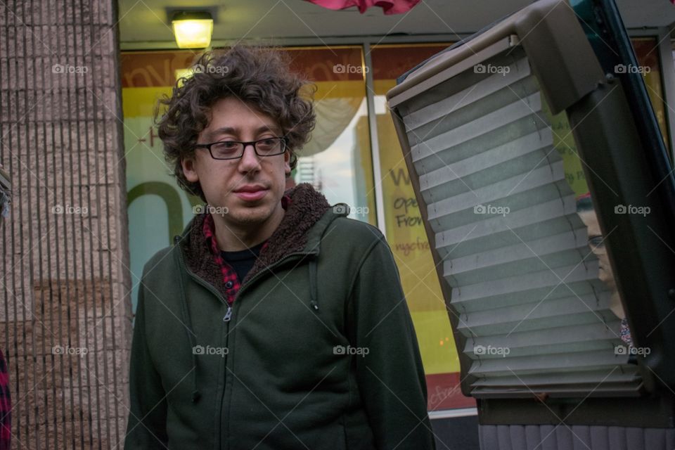 Millennial hipster man wearing glasses and a hoodie stands in front of an open van door preparing himself mentally to move yet more boxes in his NYC crosstown move.