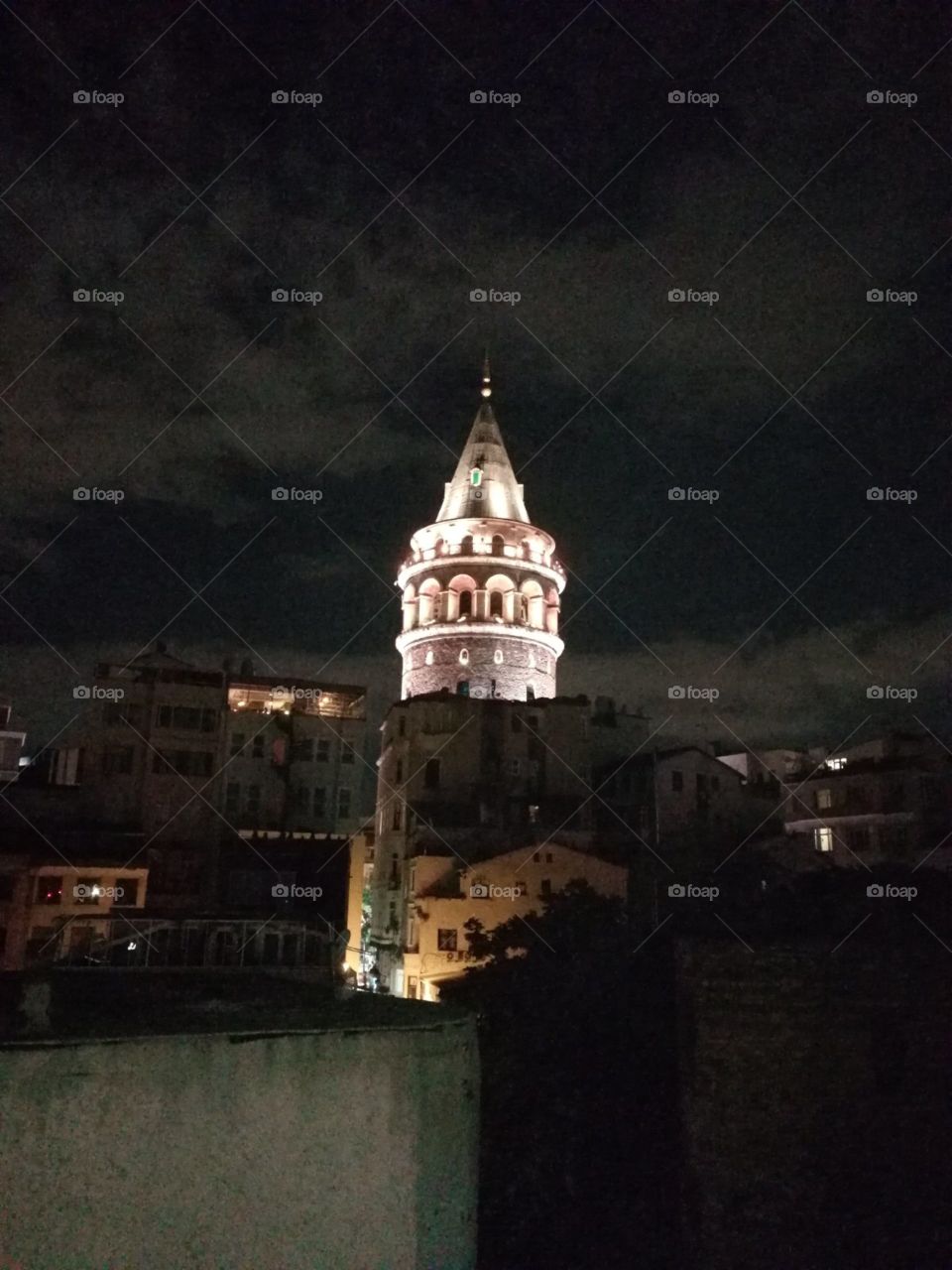 White iluminated the old Galata tower night view from the terrace of other house.