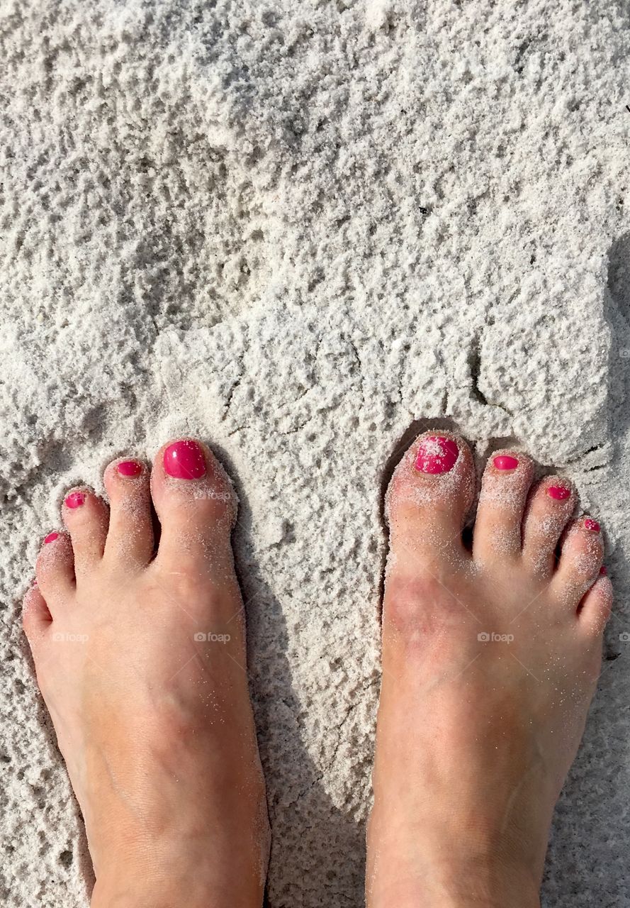 Pink toes in the white beach sand
