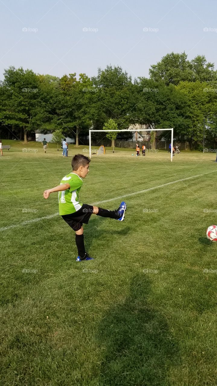 boy kicks soccer ball very happily.