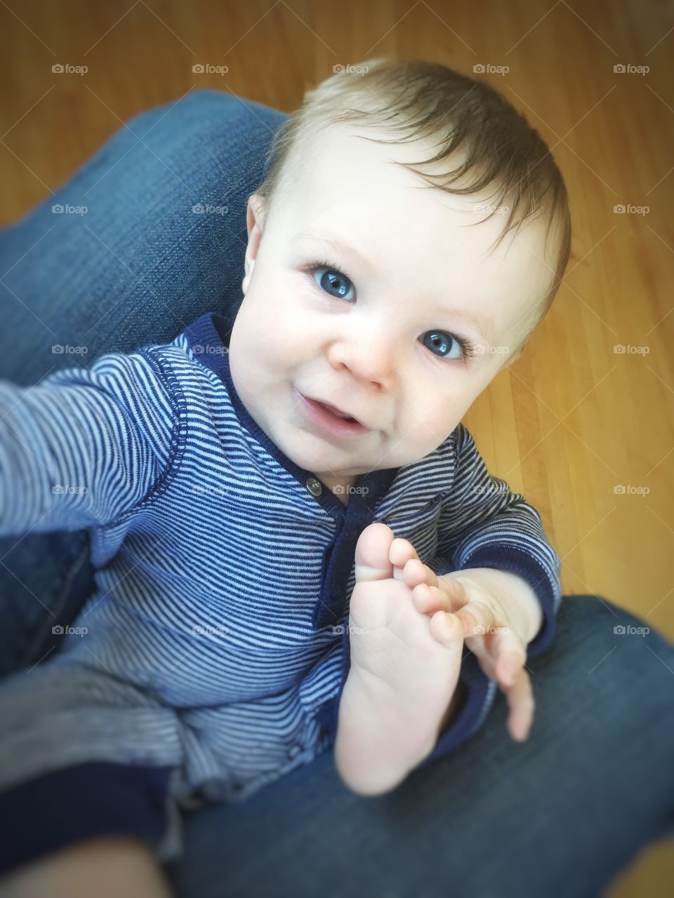 Cute little boy sitting on person's lap