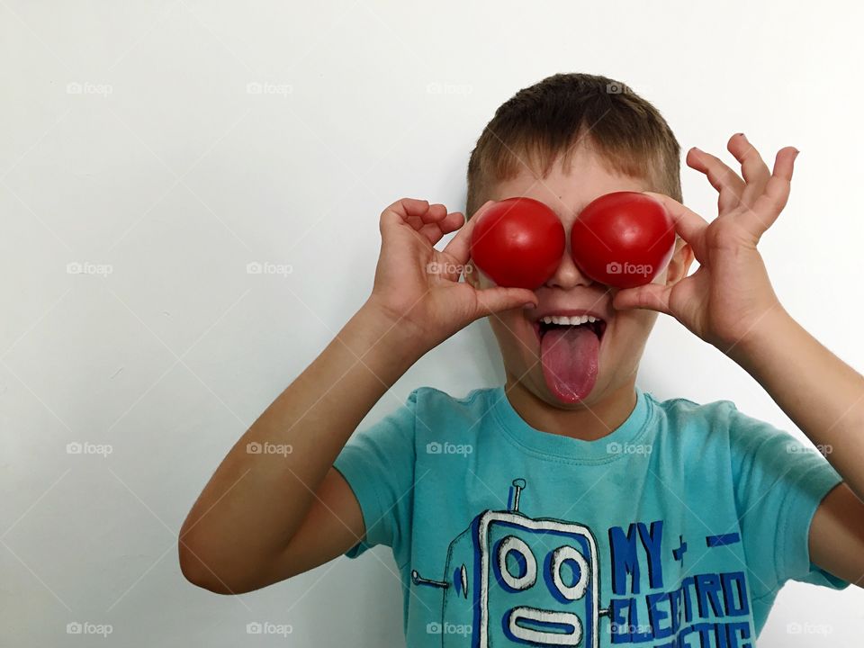Boy holding tomatoes in front of his eyes