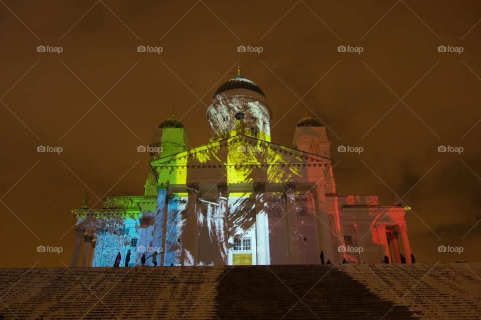 Helsinki, Finland - January 10, 2016 - People watching Ilon kuvia (Images of Joy) light art installation displayed on the exterior of Helsinki Cathedral at the Lux Helsinki light arts festival on 10 January 2016.