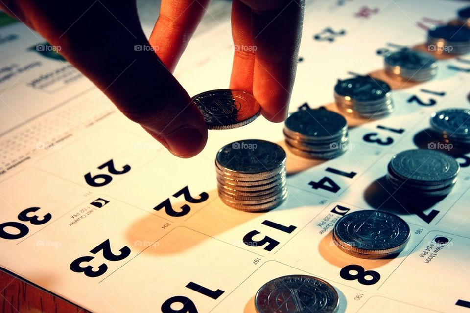 Hands piling or stacking coins on a calendar