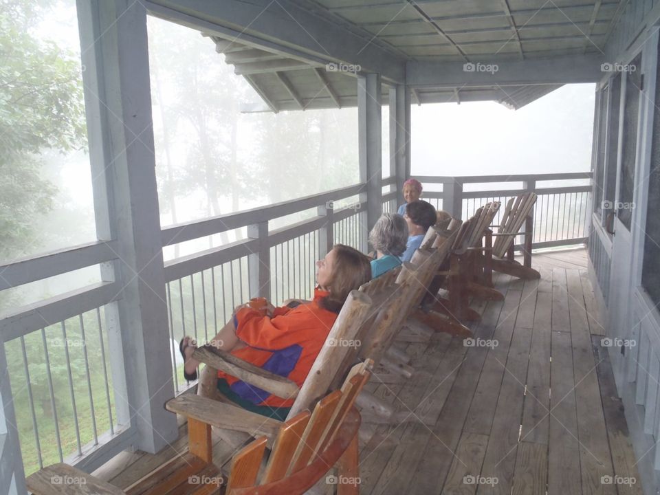 Women in rocking chairs on porch in fog