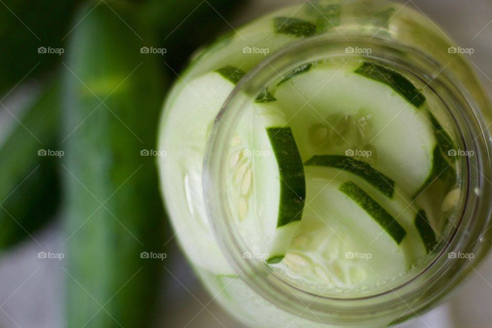 Fruits! - Overhead view of cucumber-infused water in a half-gallon mason jar with cucumbers on a white dish towel