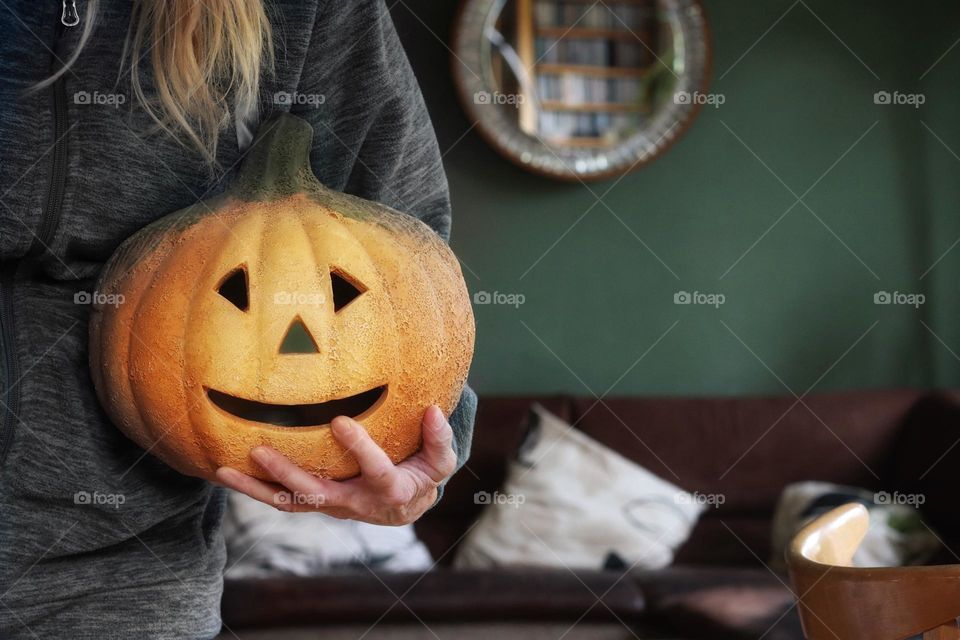 A woman carries a Halloween pumpkin in her arms to decorate the living room