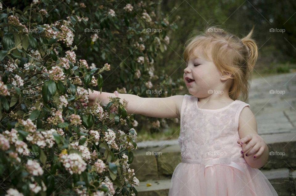 Cute girl standing in front of fresh flower plant