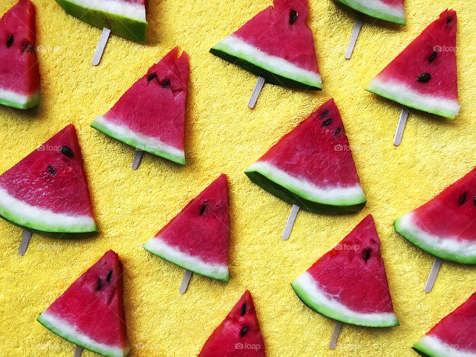 Colorful flat lay pattern made of Many slices of red watermelon on yellow textile background 