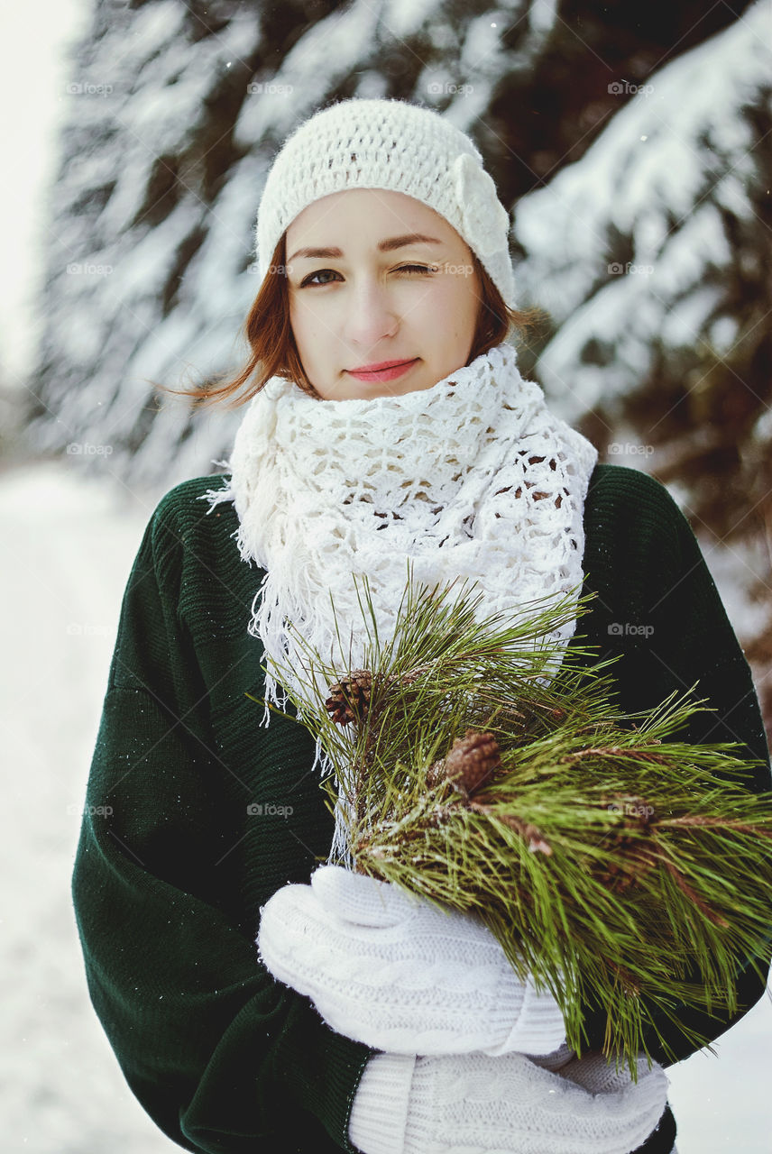 Winter portrait of young redhead woman in green sweater in snowcovered winter park.