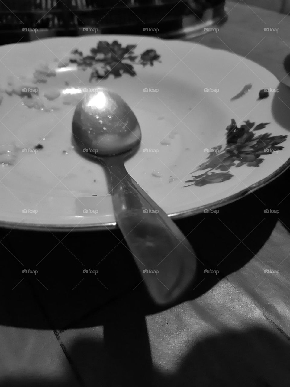 A fine art style of empty plate and a spoon after someone finished eating his food