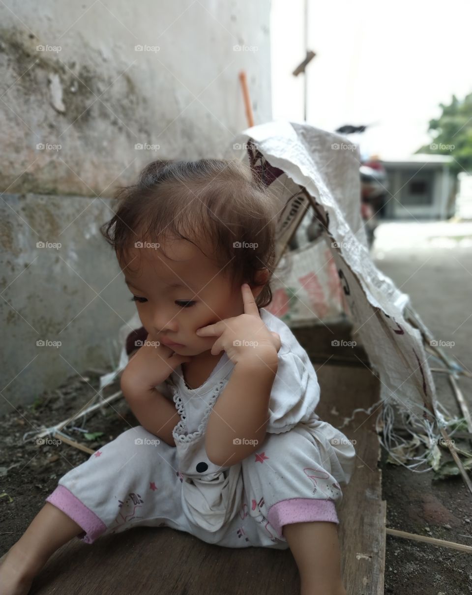 sad cute girl sit in front of old house of poor building