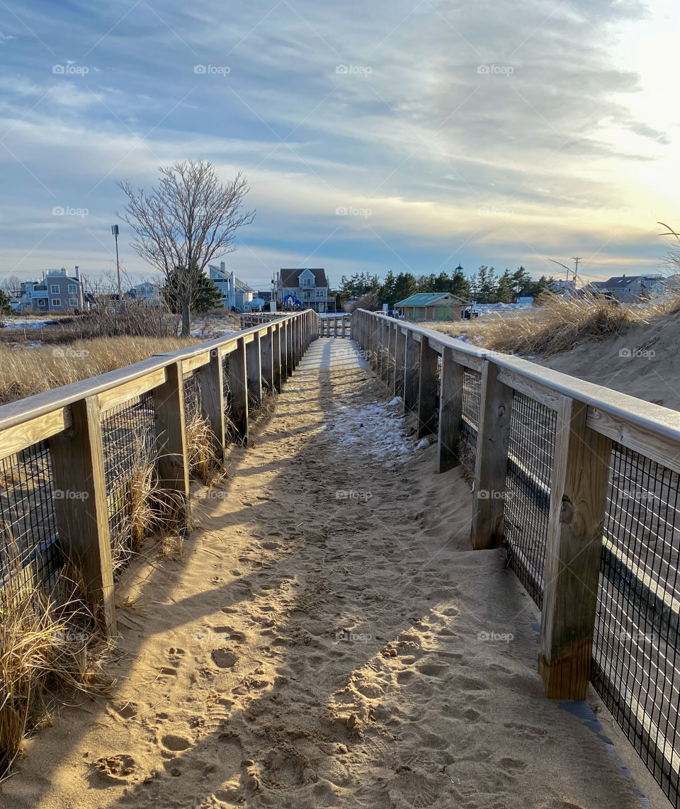 Sandy path off of the beach boardwalk to the parking lot on a cold and windy winters day. 