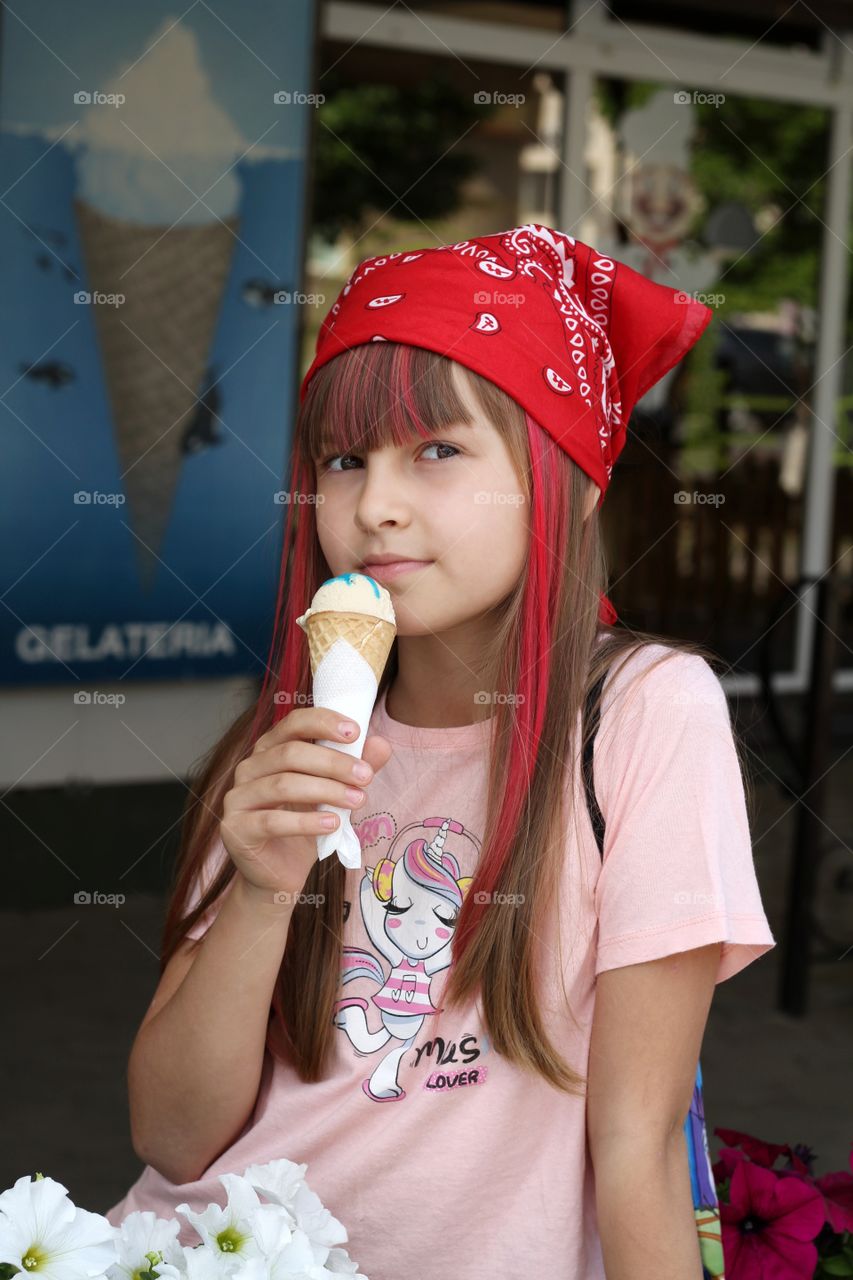 девочка Милана есть мороженое в летнем кафе