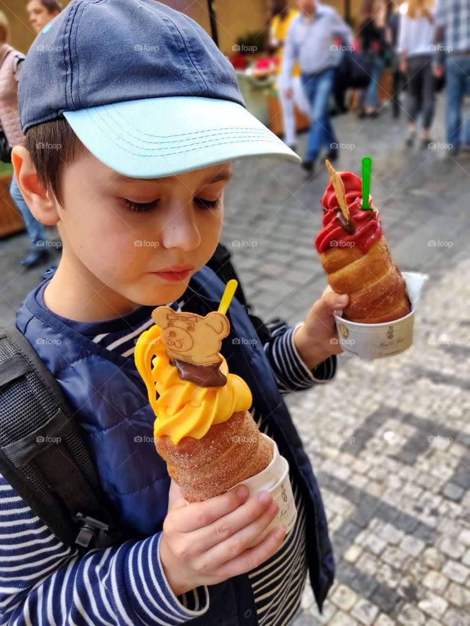 boy eating czech delicacy trdelnik with ice cream