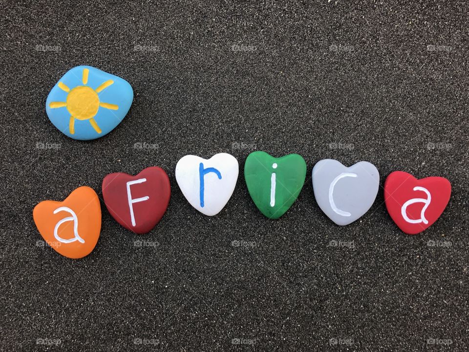 Africa, souvenir with colored heart stones over black volcanic sand