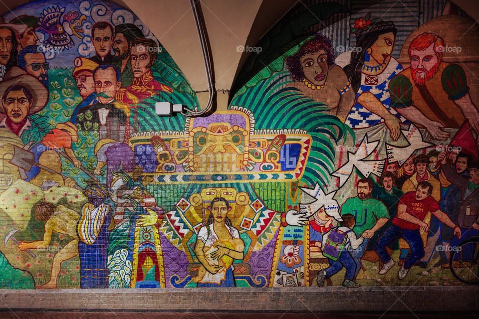 Bologna, Italy colorful wall graffiti under the arches. Vibrant street art mural by Colombian artist Luis Gutierrez at via Zamboni 38 depicting 500 years of the Conquest of America.