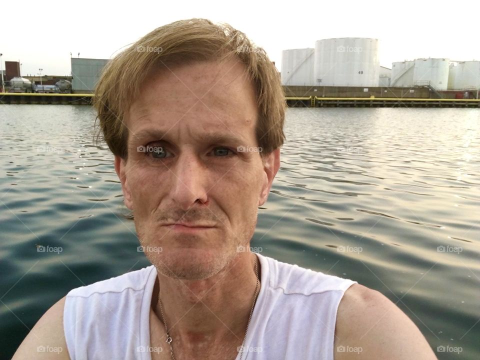 This is „Timothy Trespas“, my significant other for many years standing by the ocean at „Newtown Creek“ by the „Pulaski Bridge“ in LIC, Queens with a backdrop of the „East River“. 2019. Hypnotic Productions
