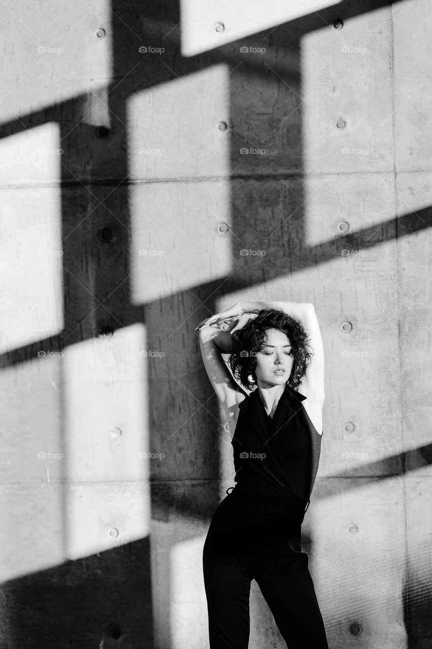 Black and white portrait of woman in black costume. Contrast lights and shadows