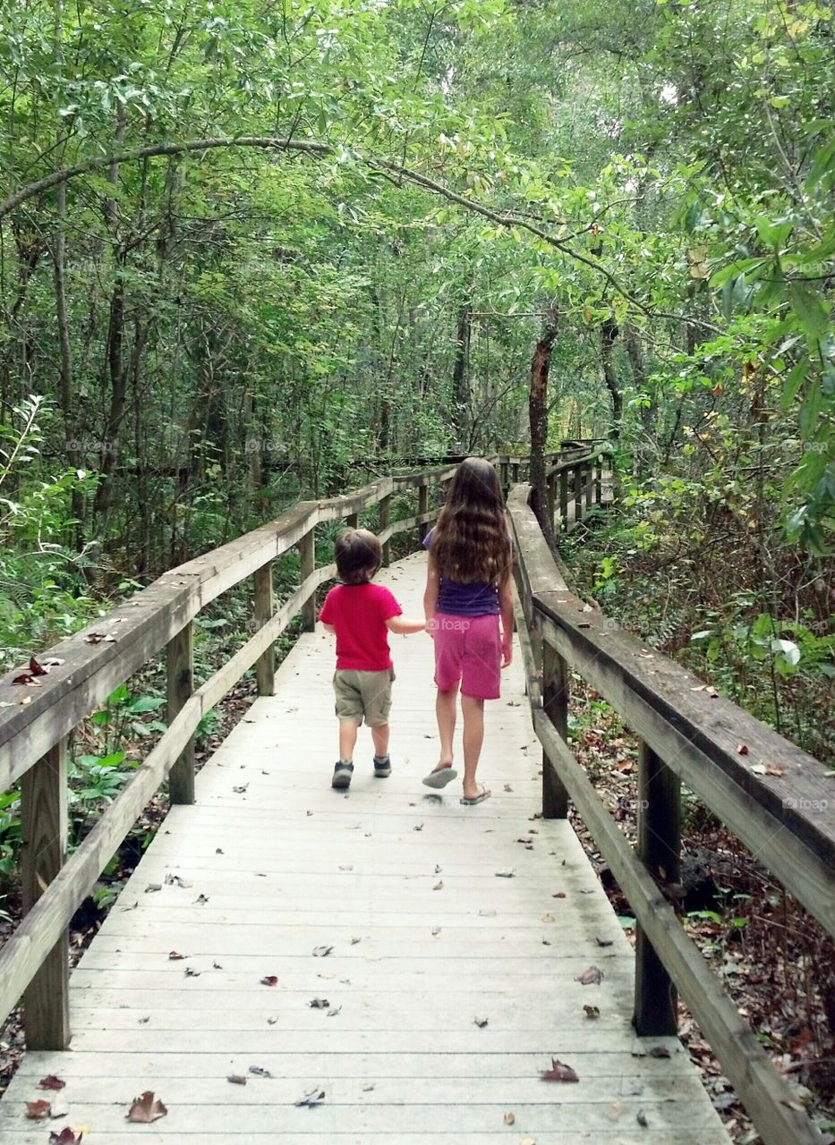 Boy and girl holding hands in nature / nature trail / siblings