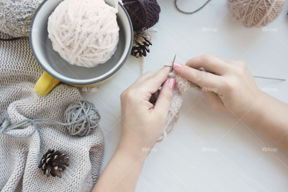 women's hands are knitting with light plush yarn