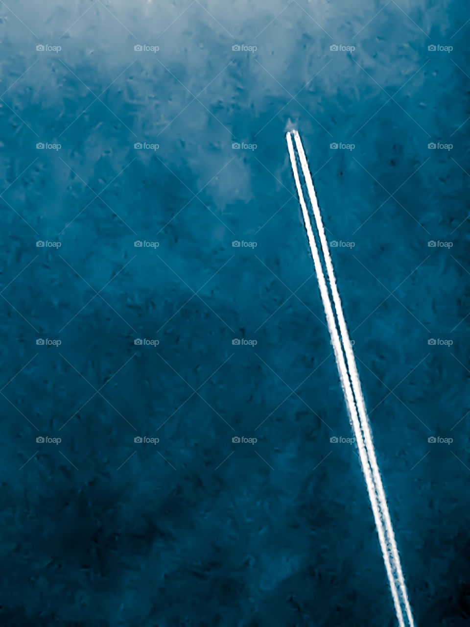 A jet flying across the crystal blue skies followed by its pure white plumes of exhaust. 