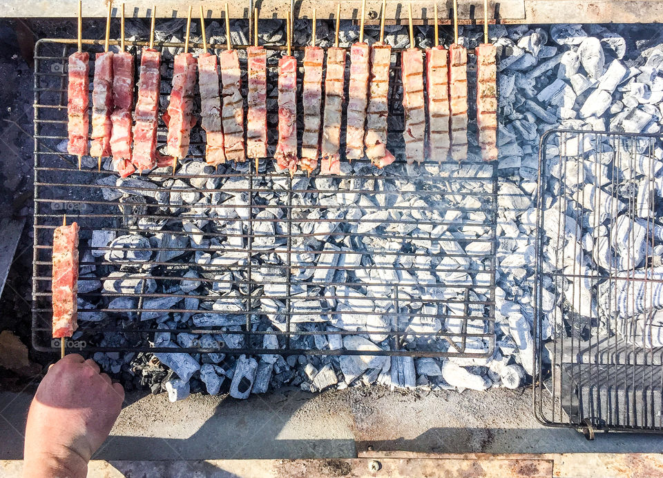 Man Roasting Barbecue On Grill Sausages And Pork Meat
