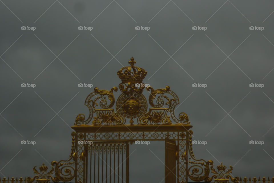 Foggy sky behind a gold and huge gate.