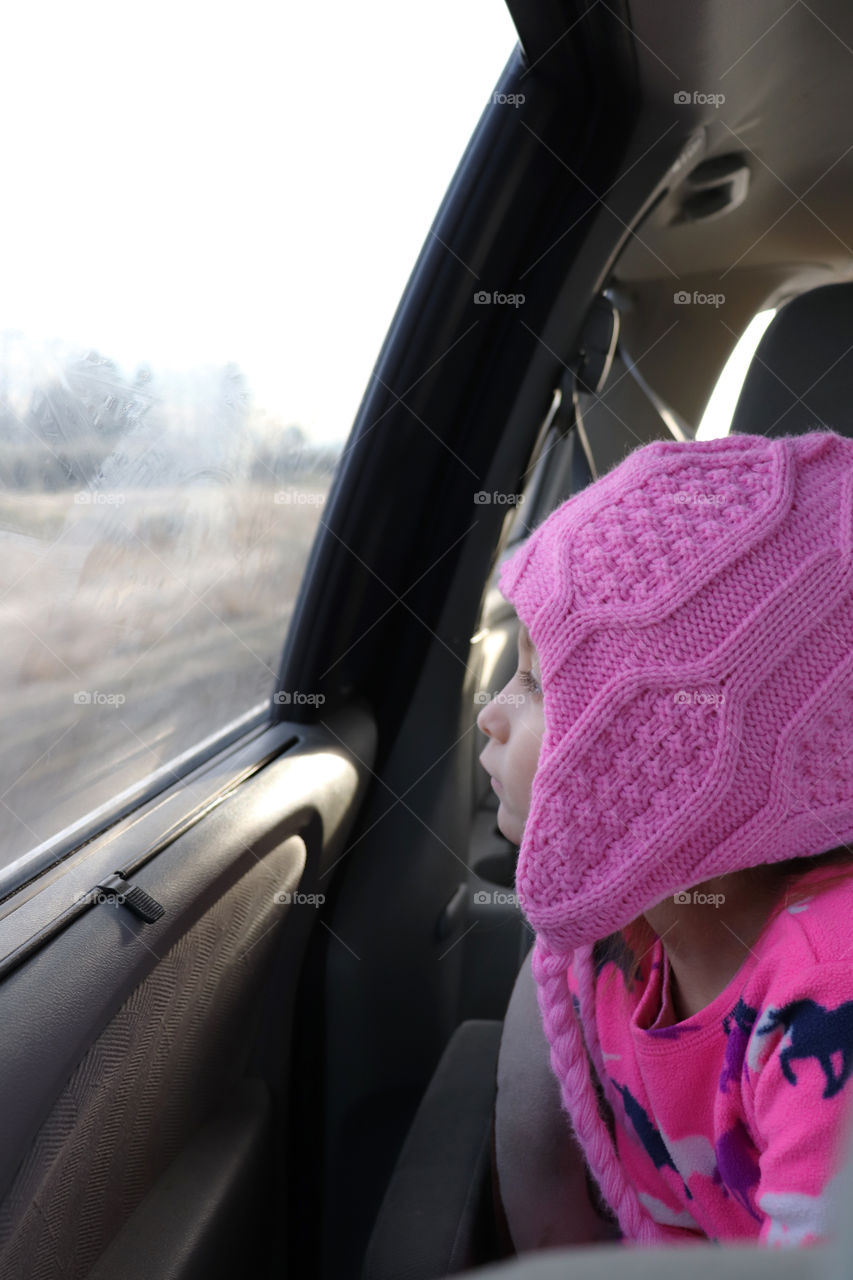 Child looking out the window of a driving car