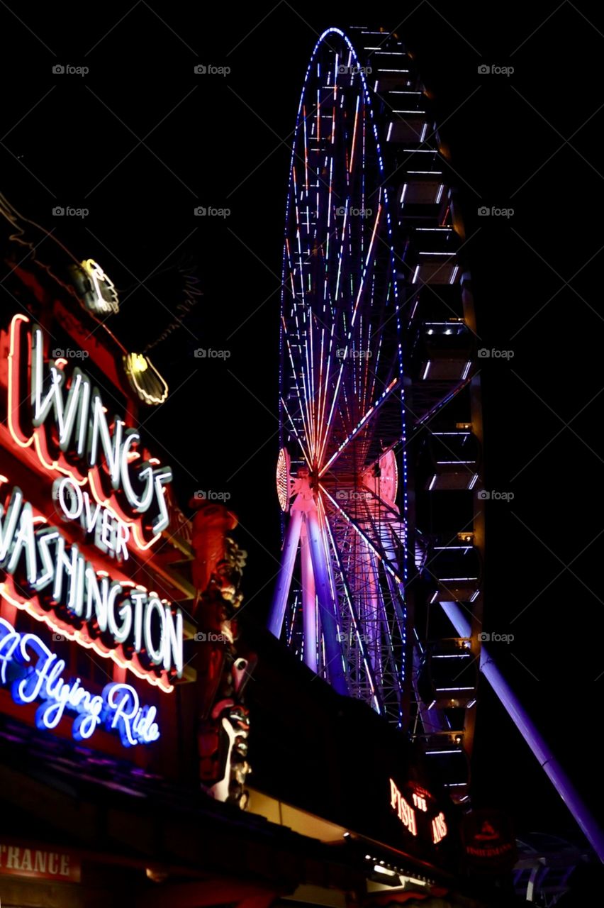 The neon lights of night life at the famous wharf near Pikes Place Market in downtown Seattle Washington, featuring the famous Ferris wheel on the wharf. 