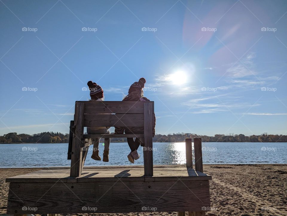 girls on a lifeguard bench at the sunny beach in the winter