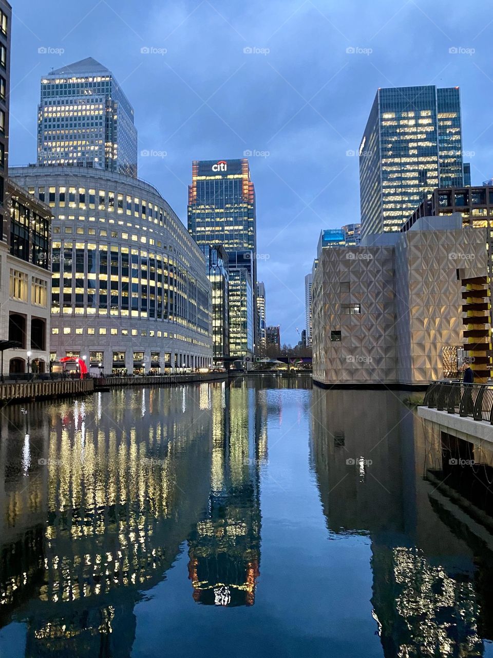 Buildings with illuminated windows during evening and reflection at water